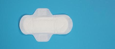 Woman sanitary napkins on blue background. Top view. photo