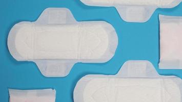 Woman sanitary napkins on blue background. Top view. photo