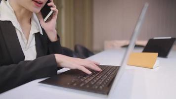 giovane donna d'affari che lavora sodo con una conversazione telefonica mentre è impegnata a controllare gli ordini dalla chiamata del cliente, multitasking nello spazio di lavoro condiviso, consulenza finanziaria che si occupa di casi problematici dei clienti video