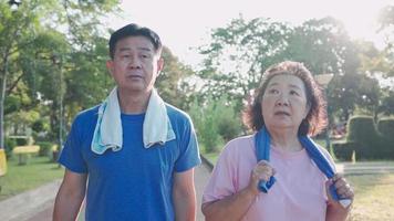 Aziatisch senior koppel dat samen een wandeling maakt in recreatiepark, gezonde pensioenlevensstijl, gezinslidrelatiedoel, gelukkig lachend koppel van middelbare leeftijd tijdens ochtendoefening