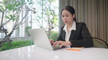 mujer de negocios trabajadora en traje de trabajo formal trabaja sola sola con una computadora portátil, gestión de análisis de datos, joven emprendedora piensa en el planificador, ambiente de trabajo, motivación laboral positiva video