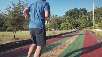 hombre adulto medio asiático corriendo en la pista de atletismo en el parque recreativo en un día soleado en cámara lenta. actividad de estilo de vida saludable de jubilación. la motivación de atención médica regresa después de la pandemia de covid19 video