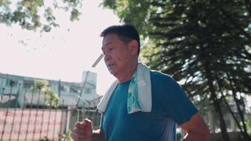 Asian senior man running inside the park on a sunny day in slow motion. Retirement healthy lifestyle activity. Elderly Health care insurance plan, in the summer hot weather, metabolism immune system video