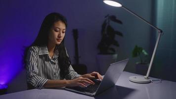 freelance feminino sentado na minha mesa com um laptop durante a noite em sua casa video