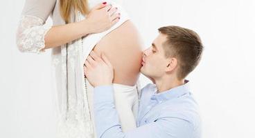 joven besa un vientre embarazado aislado foto