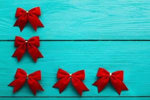 Frame of red bows on blue wooden background with copy space. photo