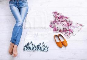 Stylish outfit with accessories and female legs on white wooden background. Top view and copy space photo