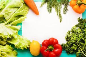 Parsley, pepper, carrot, lemon and recipe paper on blue wooden kitchen table. Top view photo