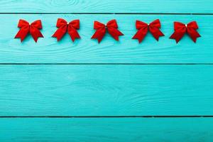 Frame of red bows on blue wooden background with copy space. photo