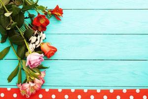 Frame of flowers and tablecloth in polka dots on blue wooden table. Top view and selective focus. Copy space. Mock up. Valentine photo