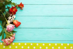 Frame of flowers and tablecloth in polka dots on blue wooden kitchen workplace. Top view and selective focus. Copy space photo