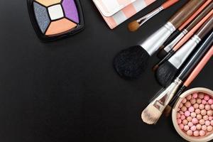 Cosmetics on black background and make up tools. Top view and mock up. Copy space. photo
