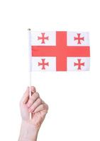A hand holds the flag of Georgia against a white insulated background. photo