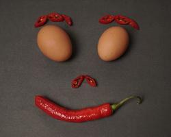 The combination of fresh tomatoes, red chilies and eggs forms a smiling face. Cooking ingredients ready to be served. focus blur, background inspiration. black and red color combination. photo