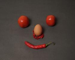 la combinación de tomates frescos, chiles rojos y huevos forma una cara sonriente. ingredientes de cocina listos para ser servidos. desenfoque de enfoque, inspiración de fondo. combinación de colores negro y rojo. foto