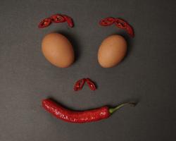 la combinación de tomates frescos, chiles rojos y huevos forma una cara sonriente. ingredientes de cocina listos para ser servidos. desenfoque de enfoque, inspiración de fondo. combinación de colores negro y rojo. foto