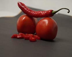 The combination of fresh tomatoes, red chilies and eggs forms a smiling face. Cooking ingredients ready to be served. focus blur, background inspiration. black and red color combination. photo