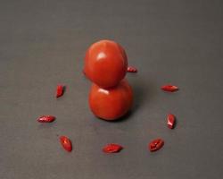 The combination of fresh tomatoes, red chilies and eggs forms a smiling face. Cooking ingredients ready to be served. focus blur, background inspiration. black and red color combination. photo