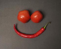 la combinación de tomates frescos, chiles rojos y huevos forma una cara sonriente. ingredientes de cocina listos para ser servidos. desenfoque de enfoque, inspiración de fondo. combinación de colores negro y rojo. foto