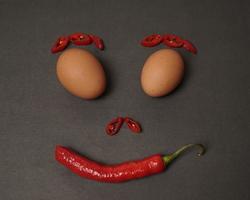 The combination of fresh tomatoes, red chilies and eggs forms a smiling face. Cooking ingredients ready to be served. focus blur, background inspiration. black and red color combination. photo