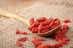 Red dried goji berries in wooden spoon photo