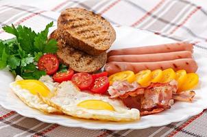 English breakfast - fried eggs, bacon, sausages and toasted rye bread photo