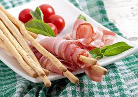 Grissini bread sticks with ham, tomato and basil photo