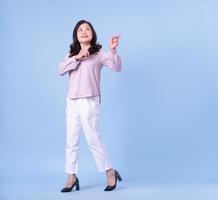 Full length image of middle aged Asian woman on blue background photo