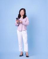 imagen completa de una mujer asiática de mediana edad con fondo azul