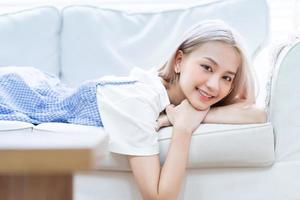 Portrait of young Asian girl lying on sofa at home photo