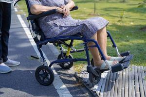 Caregiver help and care Asian senior or elderly old lady woman patient sitting and happy on wheelchair in park, healthy strong medical concept. photo