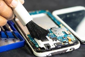 El técnico usa un cepillo y una bola de aire para limpiar el polvo en la placa de circuito de la computadora. reparación de tecnología de actualización y mantenimiento.