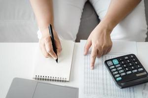 Woman is calculating annual tax with calculator and filling form of Individual Income Tax Return. Season to pay Tax and Budget planning concept. photo