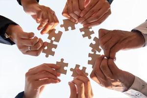 The hand of a businessman holding a paper jigsaw And solving the puzzle together. The business team assembles a jigsaw puzzle. A business group wishing to bring together the puzzle pieces photo