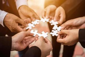 The hand of a businessman holding a paper jigsaw And solving the puzzle together. The business team assembles a jigsaw puzzle. A business group wishing to bring together the puzzle pieces photo