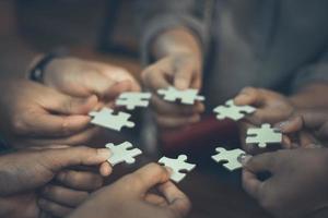 Team placing four puzzles jigsaw together for team concept photo