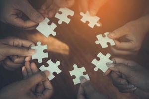 Hand of diverse people connecting jigsaw puzzle. Concept of partnership and teamwork in business photo