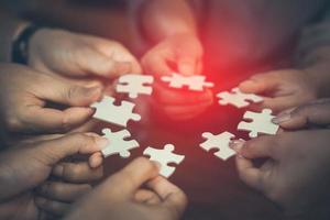 Hand of diverse people connecting jigsaw puzzle. Concept of partnership and teamwork in business photo