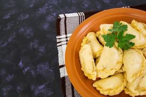 Delicious dumplings with cabbage on dark background. Top view photo