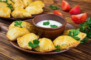 Delicious baked empanadas on wooden background photo