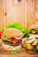 Delicious handmade burger on wooden background. Close view