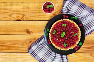 Delicious tart with custard and raspberry on wooden background photo