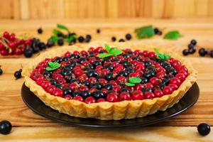 deliciosa tarta con natillas y grosellas sobre fondo de madera foto