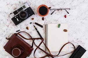 Flat lay, top view office table desk. Desk workspace with retro camera, diary, pen, glasses, case, cup of coffee on white background. photo