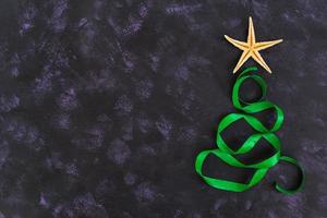 Christmas tree made of ribbon and starfish on dark background. Top view photo