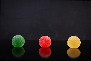 Colorful marmalade isolated on dark background. Delicious jujube balls. photo