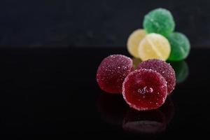 Colorful marmalade isolated on dark background. Delicious jujube balls. photo