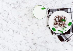 Chocolate cookies and a glass of milk on white background. Top view photo