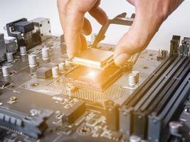 Hold the CPU handle and insert it into the CPU slot on the motherboard. It's an old motherboard, lots of dust. Put orange light on the cpu slot. There is a RAM slot next to it. There is a capacitor. photo