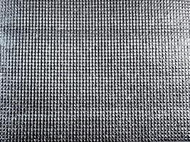 The surface of the silver reflector reflects light, the surface pattern is a small rectangular grid. photo